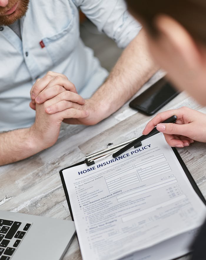 About Us Two adults reviewing a home insurance policy document on a table with electronic devices.